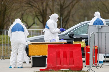 Coronavirus kontrol noktası. Korumalı kostümlü sağlık görevlileri koronavirüs için kan örnekleri alırlar (Covid-19)