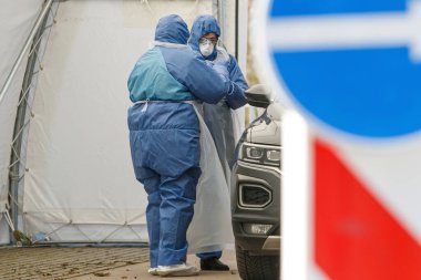 Coronavirus kontrol noktası. Korumalı kostümlü sağlık görevlileri koronavirüs için kan örnekleri alırlar (Covid-19)