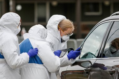 Coronavirus kontrol noktası. Korumalı kostümlü sağlık görevlileri koronavirüs için kan örnekleri alırlar (Covid-19)