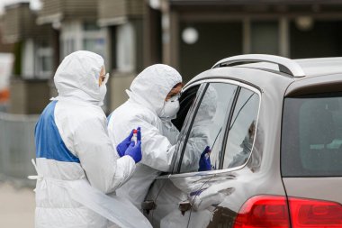 Coronavirus kontrol noktası. Korumalı kostümlü sağlık görevlileri koronavirüs için kan örnekleri alırlar (Covid-19)