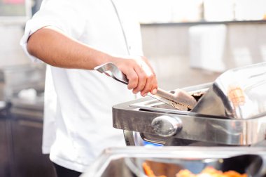 Usta şef açık mutfakta balık pişiriyor.