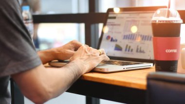 Dikiz diz üstü kafede üzerinde erkek çalışıyor. Dijital cihazlar üzerinde ahşap masa kullanan müşteriler. İş rapor ve veri ağ dizüstü ekran üzerinde analiz işadamı. 