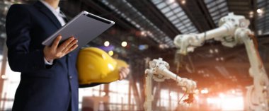 Businessman in a future construction site, Robotics engineer using tablet with control over system by application, Industrial robotics, Automation robot arms machine in intelligent factory industrial. Industry 4.0 concept clipart