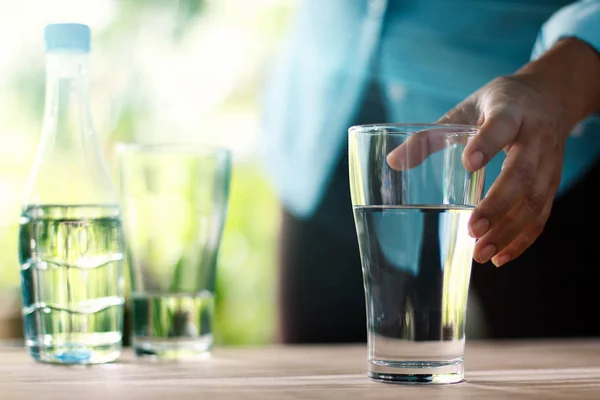 Mano Tocando Alcanzando Vaso Agua Potable Mesa Madera Fondo Verde — Foto de Stock