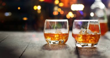 Gece ışıklar arka plan, ahşap masa üzerinde buzlu viski içer