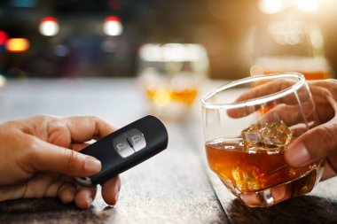Hand holding alcoholic drink, another hold car remote, Drunk driving concept. clipart