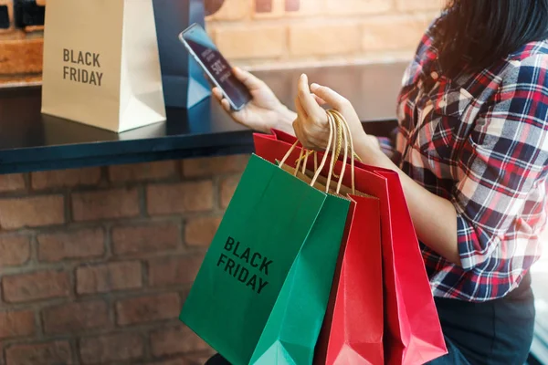 Black Friday Woman Using Smartphone Holding Shopping Bag While Sitting — Stock Photo, Image