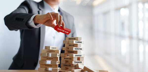 Businessman hand holding Marketing plan word on wooden blocks. Financial business. Marketing and strategy concept