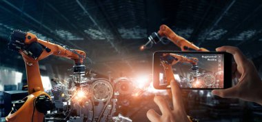 Artırılmış gerçeklik endüstrisi konsepti. El tutan mobil akıllı telefon akıllı fabrika otomotiv endüstriyel izleme sistemi yazılımı ile kaynak robotik otomatik silah makinesi kontrol etmek ve kontrol etmek için Ar uygulaması kullanın. Dijital üretim ope