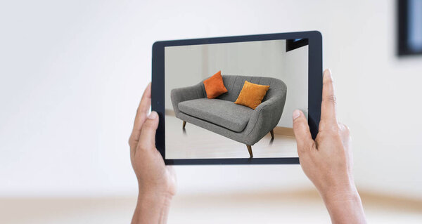 AR augmented reality. Hand holding digital tablet, AR application simulate sofa furniture and interior design  real room background