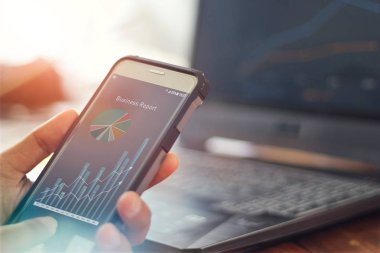 Cep telefonu kullanan bir işadamı satış verilerini ve ekonomik büyüme grafiğini analiz ediyor. İş stratejisi. iş raporu Dijital Pazarlama. 