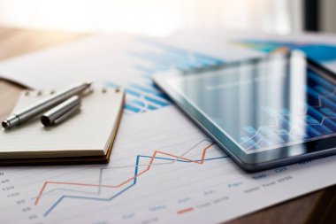 Satış verileri ve finansal iş büyüme grafiğiyle kağıt ve tablet üzerine iş belgesi.