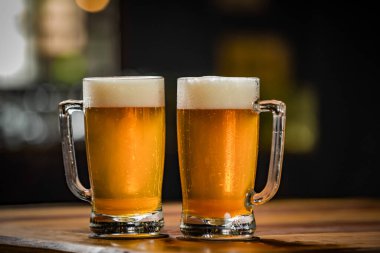 İki bardak dolusu Chopp, birinde Pilsen Chopp, diğerinde de siyah pirzola var.