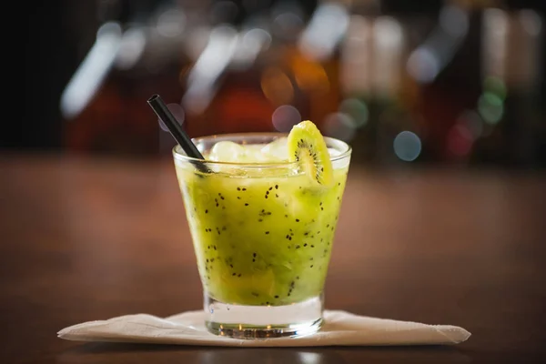 Kivi caipirinha, ahşap bir masada kirazla süslenmiş.
