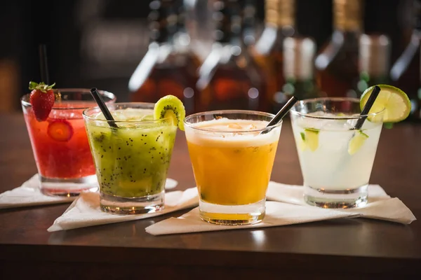 Tutku meyvesi, Kivi limonu, çilekli caipirinhas, ahşap bir masada kirazla süslenmiş.