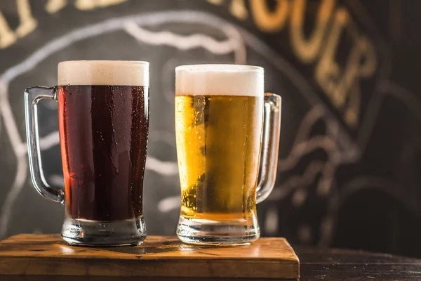 Two mugs full of chopp, one with pilsen chopp and one with dark chop on a rustic table