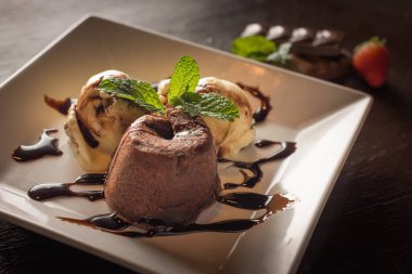 Beyaz kare tabakta dondurma ve çikolatalı tatlı.