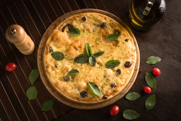 Fesleğenle süslenmiş, kiraz domatesli ve siyah zeytinli marguerita pizza.