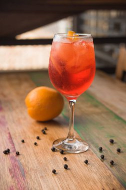 Klasik İtalyan Aperol Spritz kokteyli. Arka planda limon ve ahşap masa.