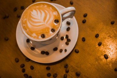 Ahşap masa arkasında bir fincan sıcak kapuçino. Kahvaltı vakti geldi. Üst Manzara. Kapalı ve seçici odaklanma