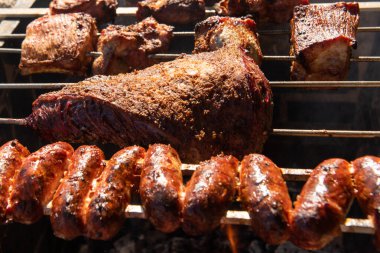 Sığır eti ve sosis yakın, kor ve altta ateş ile bir tükürükte kızarır.