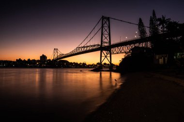 Cable, Florianopolis, Santa Catarina, Brezilya 'daki Hercilio Luz köprüsünde günbatımında renkli gökyüzü ve yapının silüetiyle kaldı.