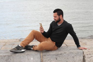 Nehrin yanındaki cep telefonlu dikkati dağılmış adam.