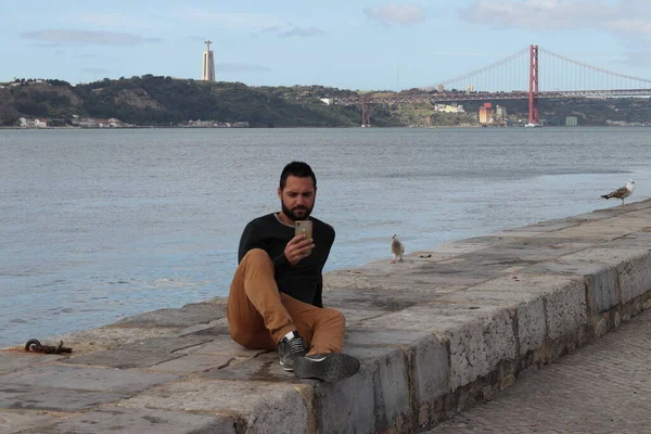 Nehrin yanındaki cep telefonlu dikkati dağılmış adam.