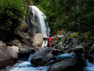 Dağlarda şelalesi olan genç bir kadın.