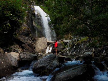 Dağlarda şelalesi olan genç bir kadın.