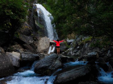 Dağlarda şelalesi olan genç bir kadın.