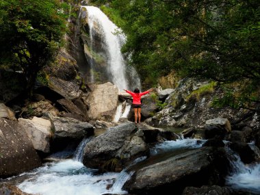 Dağlarda şelalesi olan genç bir kadın.