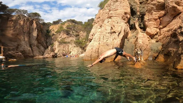 young man jumping in to the sea from a cliff in costa brava