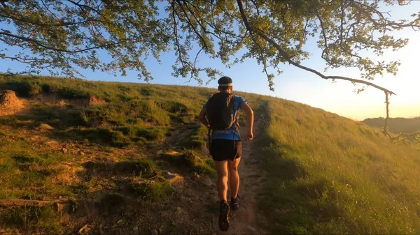 Günbatımı geçmişiyle dağlarda koşan genç bir adam.