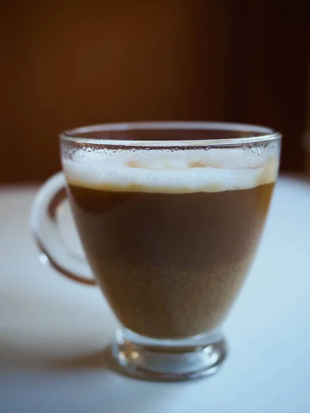 Sütlü bir fincan kahvenin beyaz bir masaya konulmuş resmi.
