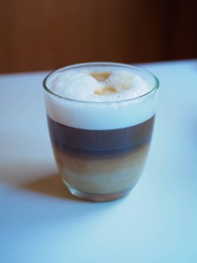 Sütlü bir fincan kahvenin beyaz bir masaya konulmuş resmi.