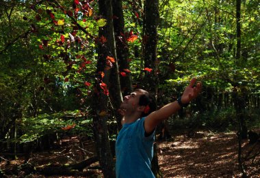 Parka yaprak atan genç adam.