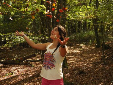 Parka yaprak atan genç bir kadın.