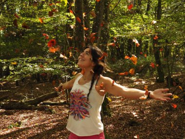 Parka yaprak atan genç bir kadın.