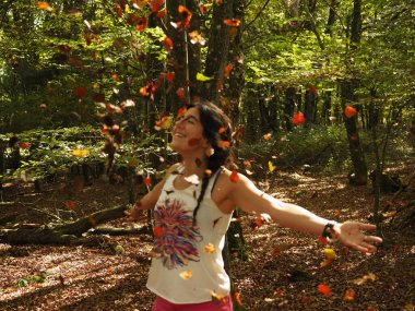 Parka yaprak atan genç bir kadın.