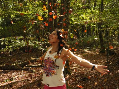 Parka yaprak atan genç bir kadın.