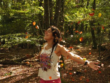 Parka yaprak atan genç bir kadın.