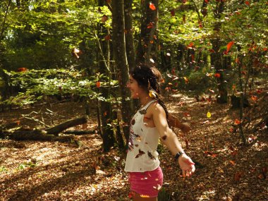 Parka yaprak atan genç bir kadın.