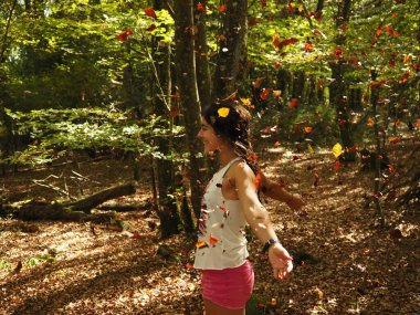 Parka yaprak atan genç bir kadın.