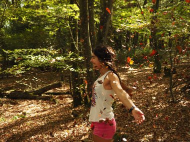 Parka yaprak atan genç bir kadın.