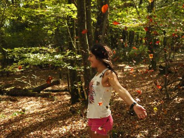 Parka yaprak atan genç bir kadın.