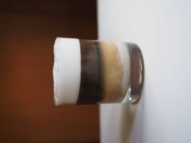 Sütlü bir bardak kahve, beyaz bir masada.