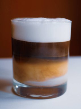 Sütlü bir bardak kahve, beyaz bir masada.