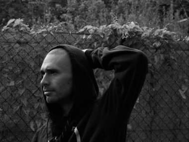 Kapüşonlu genç bir adamın siyah beyaz fotoğrafı. 