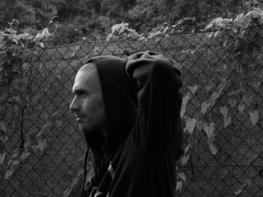 Kapüşonlu genç bir adamın siyah beyaz fotoğrafı. 